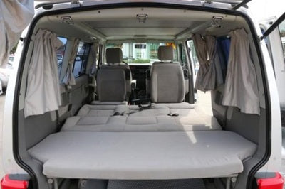 RV rental interior: rear seats fold flat, forming a spacious bed. Ideal camper van for road trips.