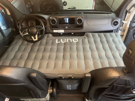 RV rental: Inflated Luno air mattress transforms a Mercedes Sprinter van's front cabin into a cozy sleeping area for travels.