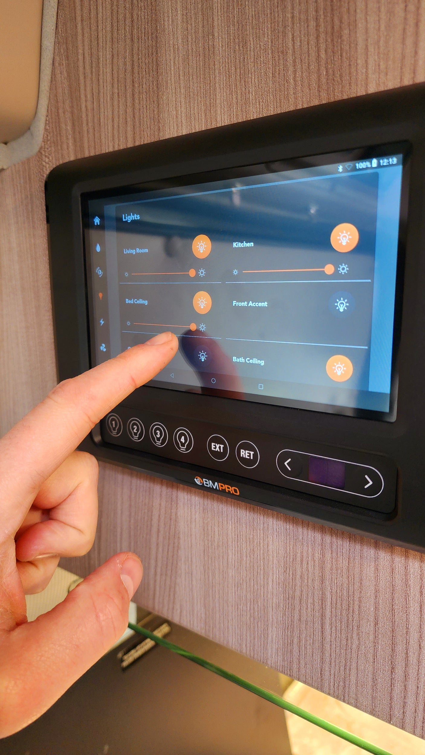 Hand adjusting a digital smart control panel to adjust interior lights in an RV rental.