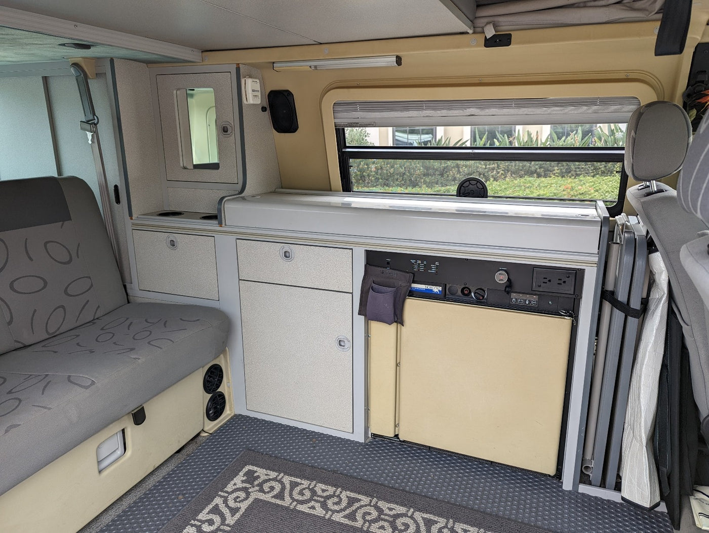 Inside an RV rental: a compact camper van interior with kitchenette, fridge, seating, and clever storage solutions. — photo 12
