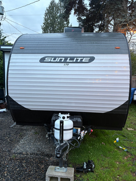 Front view of a Sun Lite Ltd travel trailer, featuring propane tank and hitch. Ideal for your next rv rental adventure!