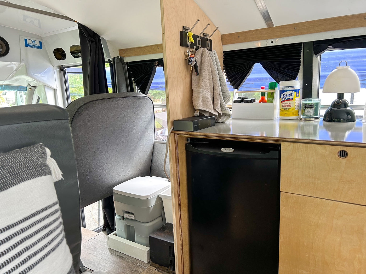 Cozy RV rental interior with kitchenette, mini-fridge, portable toilet, and storage. Perfect for compact living on the road. — photo 8