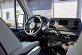 View inside an RV rental: Mercedes-Benz dashboard with wood trim, large screen, and steering wheel.