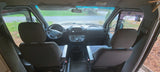 Interior view of an RV rental's cockpit, showing the driver and passenger seats, steering wheel, and dashboard.