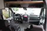 Front cabin of an RV rental showing the steering wheel, dashboard, infotainment display, and comfortable front seats.