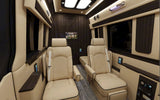Luxurious rv rental interior: cream captain's chairs, dark wood, and a TV for ultimate comfort.