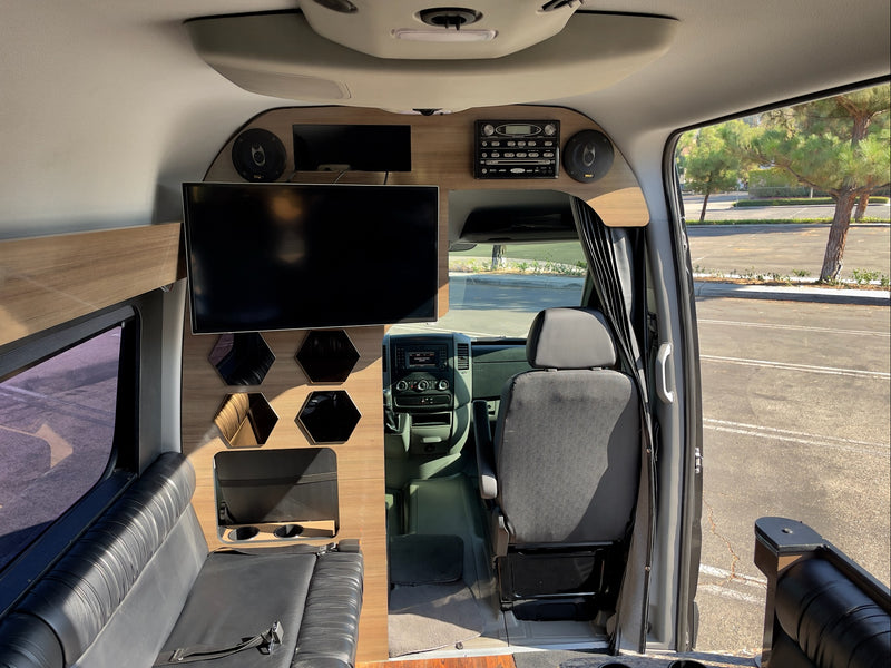Modern rv rental interior: features large TV, custom wood paneling, comfortable seating, and vehicle cockpit. — photo 14