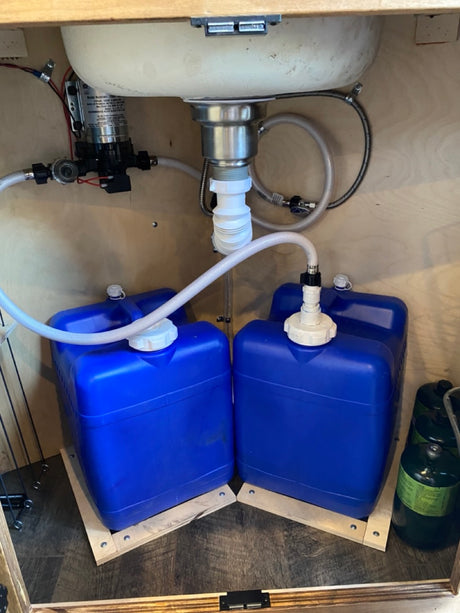 RV rental under-sink plumbing: pump, fresh/gray water tanks, and drain setup for compact living.