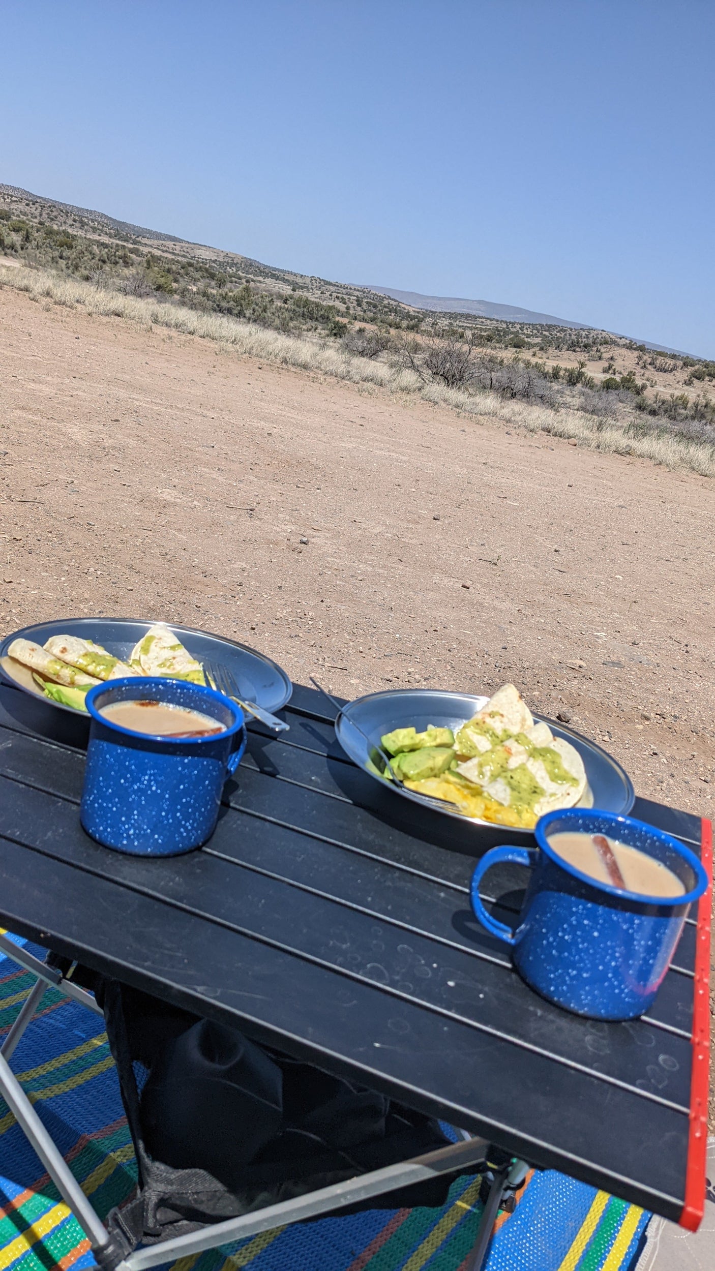Outdoor breakfast with quesadillas, avocado, and coffee on a camping table, enjoying an RV rental adventure in the desert.