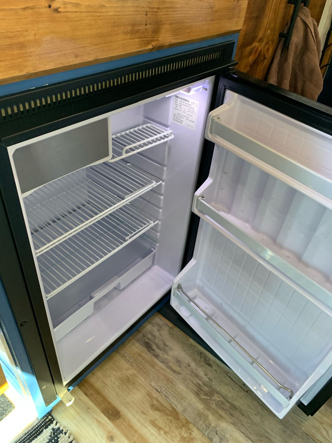 Inside a clean rv rental: an open, compact refrigerator with shelves, ready for your travel essentials.
