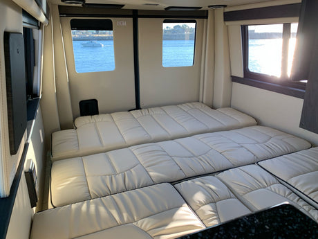 Comfortable rv rental interior featuring convertible beds, bright windows with a scenic water and boat view.