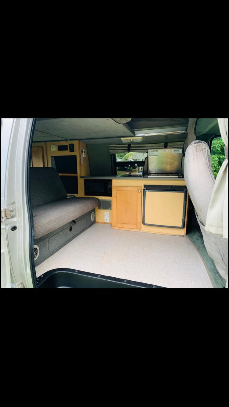 RV rental interior: Cozy camper van with sofa-bed, full kitchen including microwave, sink, and fridge. — photo 10