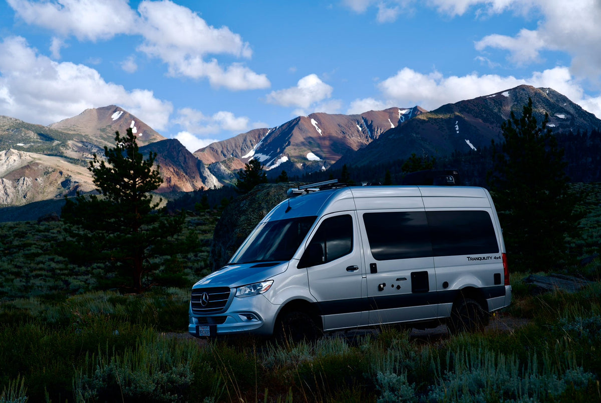  parked in a rocky desert with majestic snow-capped mountains.|Family enjoys their silver Mercedes Sprinter rv rental