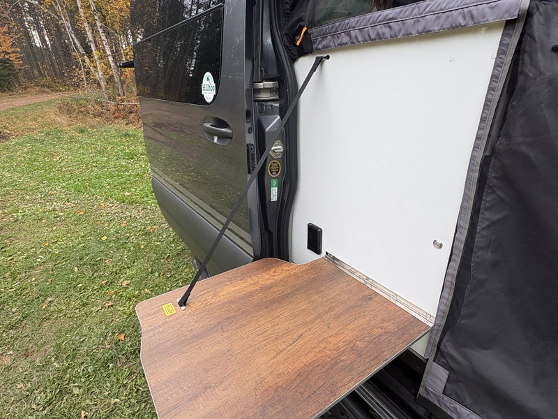  perfect for outdoor use in a scenic wooded setting.|A hand opens an outdoor electrical outlet on an RV rental. An RVIA sticker confirms it's a motorhome for temporary camping.|Customized gray Mercedes-Benz Sprinter overland van — photo 4