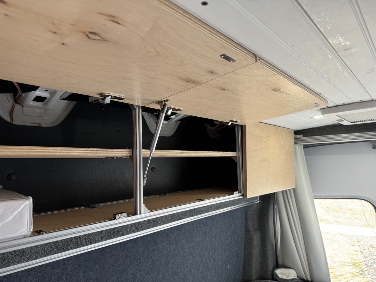 Light wood overhead cabinets in an RV rental, showcasing custom storage solutions for a well-organized camper interior.