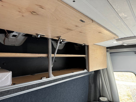 Light wood overhead cabinets in an RV rental, showcasing custom storage solutions for a well-organized camper interior.