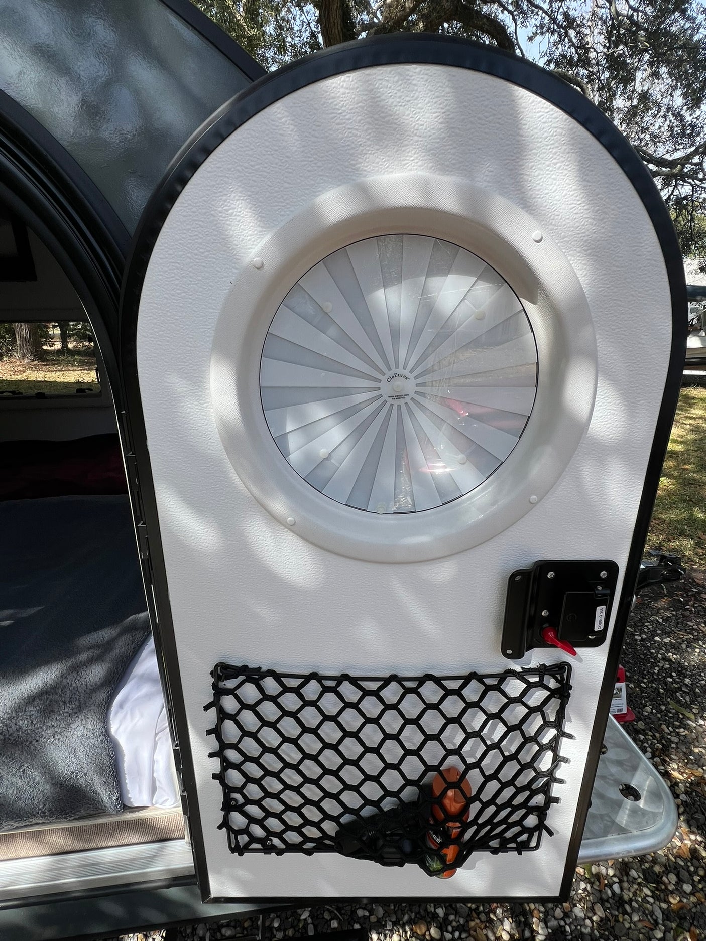 RV rental camper door: rounded white interior with circular vent, latch, and net storage for mobile living.