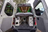 Inside an RV rental campervan: modern interior with a cozy bed, custom storage, and vibrant green LED lighting.