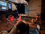 Relaxed family camping under string lights by an RV rental. Kids enjoy outdoor screen time at night.