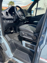 Driver's side view of a modern Mercedes Sprinter RV rental interior. Features dashboard, steering wheel, comfortable seat, and floor.