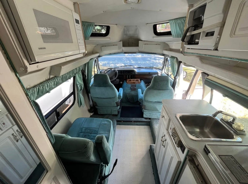  and overhead storage. Ideal for a comfortable road trip.|Explore this RV rental's inviting interior. Rear doors open to reveal plush teal seating — photo 7