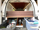 This RV rental's camper van interior showcases a cozy, foldable bed atop smart storage for all your travel gear.