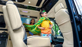 Family adventure in an RV rental: A boy in a towel cape stands proudly in a luxury van; a girl smiles behind him.
