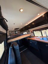 Explore this RV rental's interior: a comfortable camper van bed, functional kitchen, & Dometic fridge.