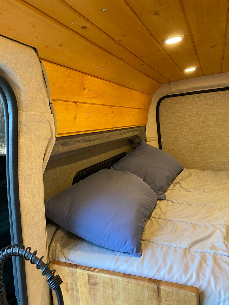 RV rental bedroom featuring a comfy bed with blue pillows, a light wood paneled ceiling, and bright recessed lighting. — photo 8