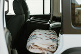 Inside an RV rental: rear seats, storage containers, a portable cooler, and a soft, patterned blanket. Ready for adventure.