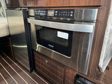 Compact kitchen in an RV rental showing a built-in microwave drawer and refrigerator for convenient use.