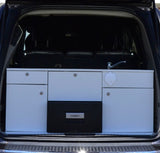 RV rental: A vehicle's trunk holds a compact camper kitchen module with sink, faucet, drawers, and Dometic fridge.