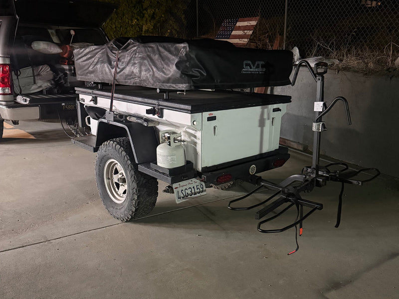 Night view of an off-road camping trailer with rooftop tent — photo 1