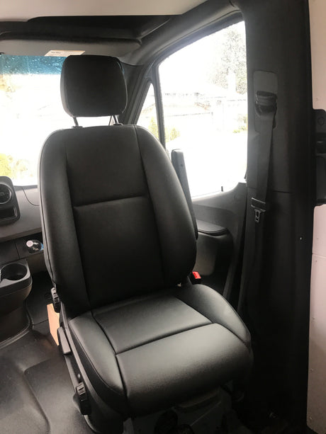 View of a spacious black passenger seat inside an RV rental van, featuring an armrest and seatbelt, ready for your travels.