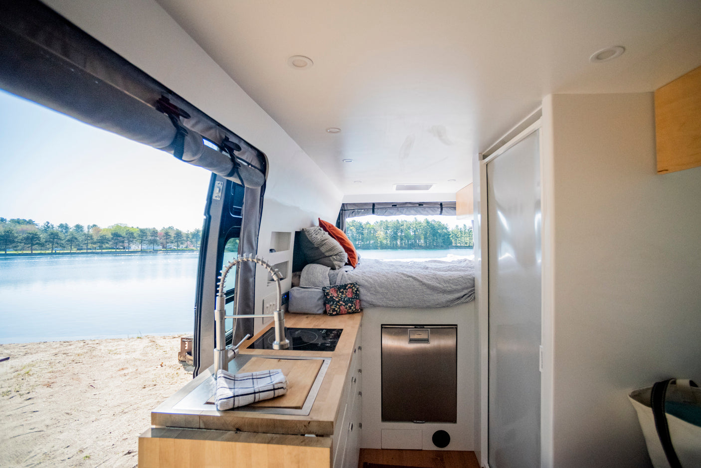 This cozy rv rental interior features a kitchen, bed, and stunning lake view, perfect for your next adventure.