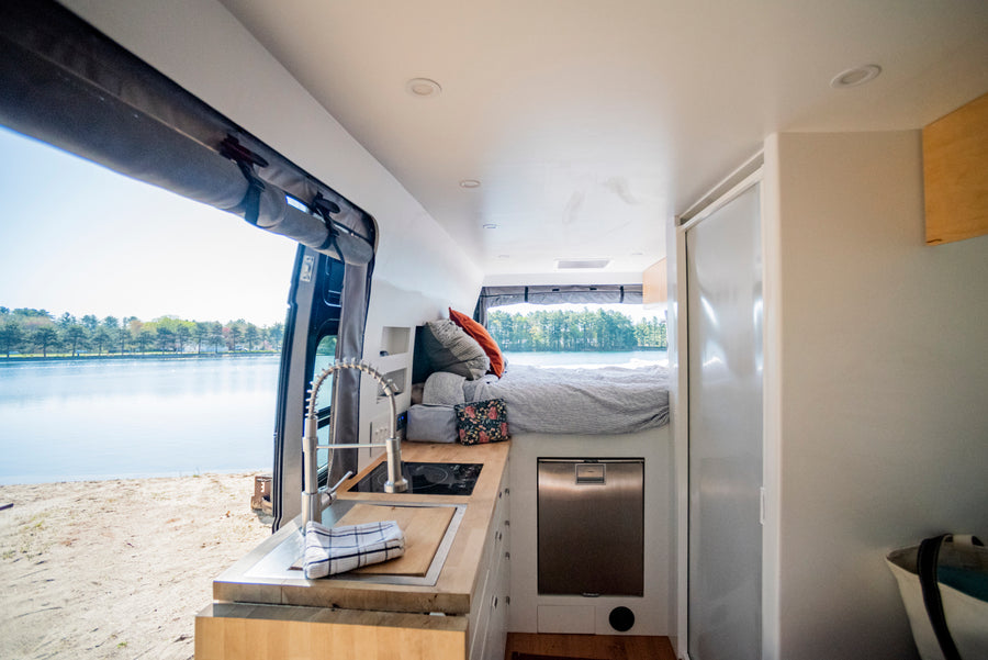 This cozy rv rental interior features a kitchen, bed, and stunning lake view, perfect for your next adventure.