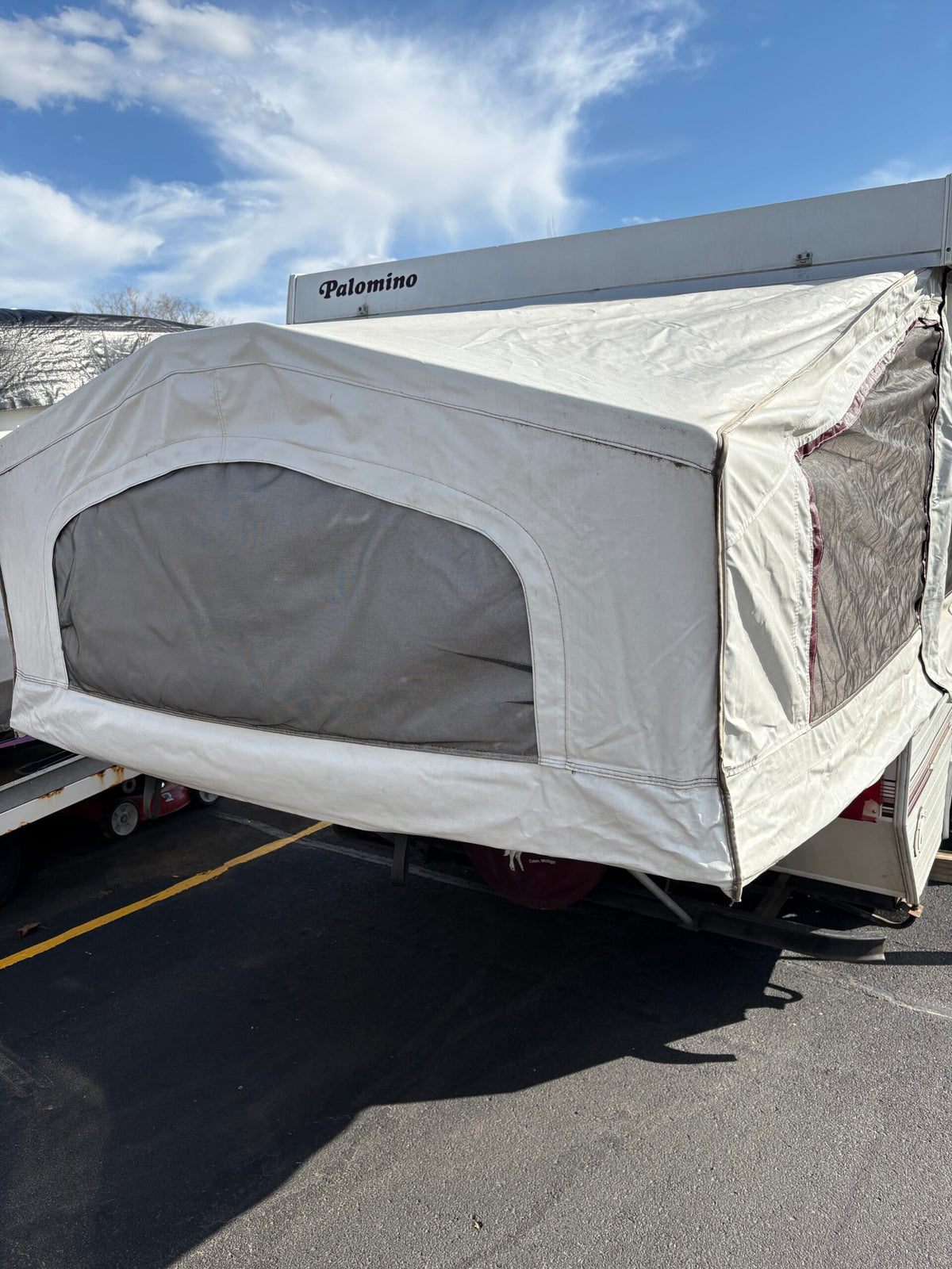 Palomino pop-up RV rental with canvas extension and mesh windows, parked on asphalt under a blue sky. — photo 4