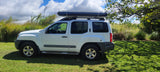White SUV with a roof tent, parked on grass. An RV rental alternative for your outdoor adventures.