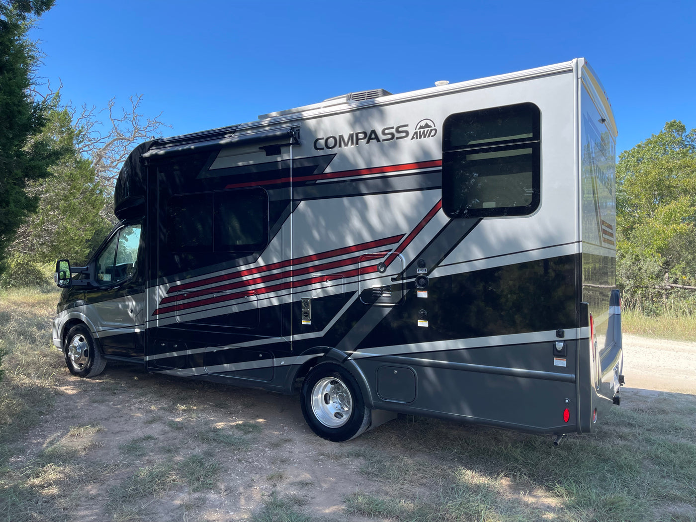 This sleek Compass AWD RV, perfect for an rv rental adventure, is parked outdoors. Its modern design features black, gray, and red accents. — photo 6