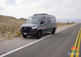 Moterra RV rental: a gray Mercedes Sprinter campervan on a desert road, ready for adventure.