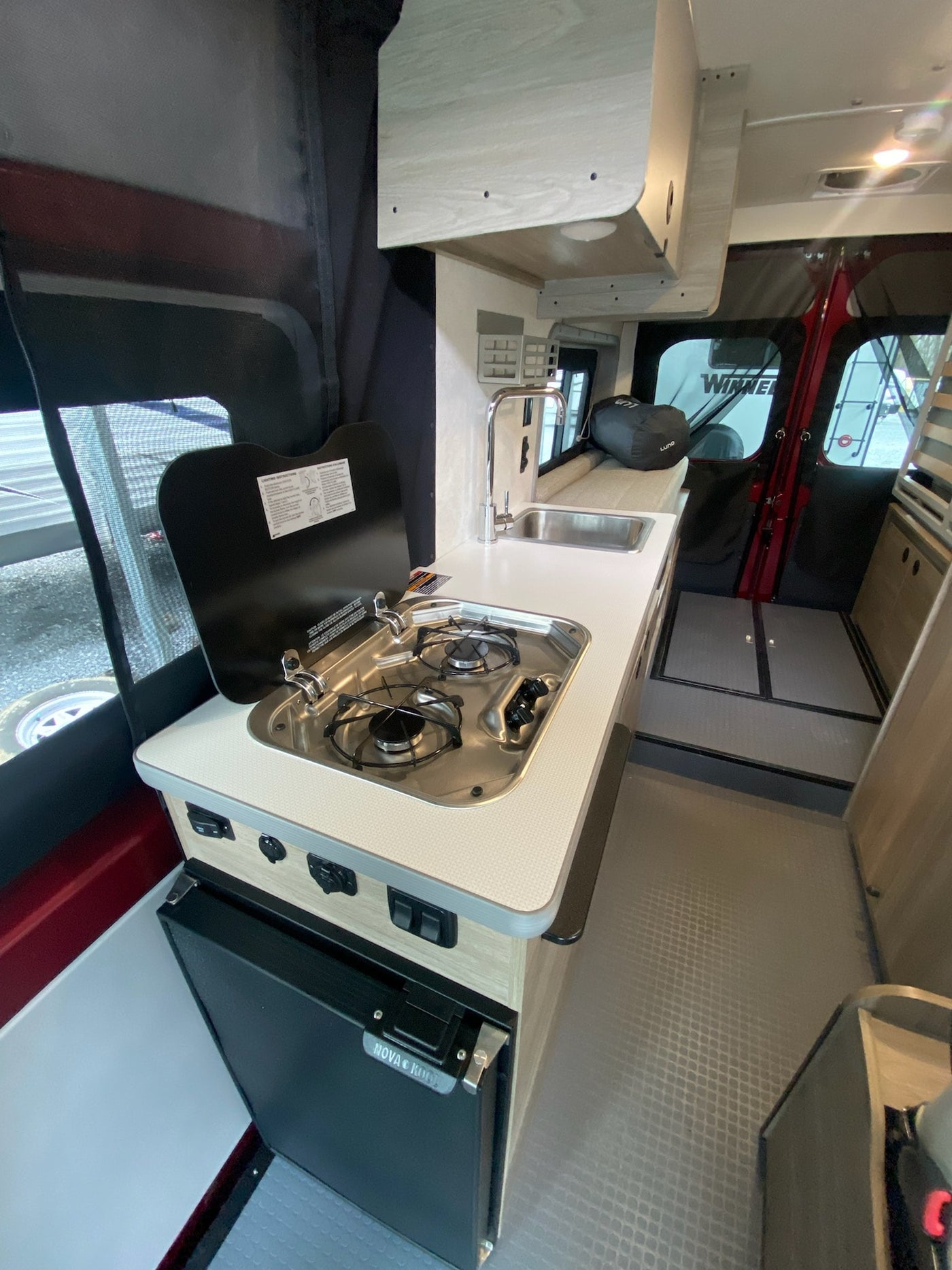 Explore the compact and functional interior of an RV rental camper van, featuring a kitchenette with a sink, stove, and fridge. — photo 8