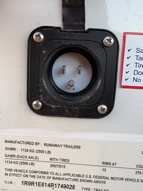 RV rental trailer's 15A shore power inlet, displaying Runaway Trailers VIN and manufacturing specifications.