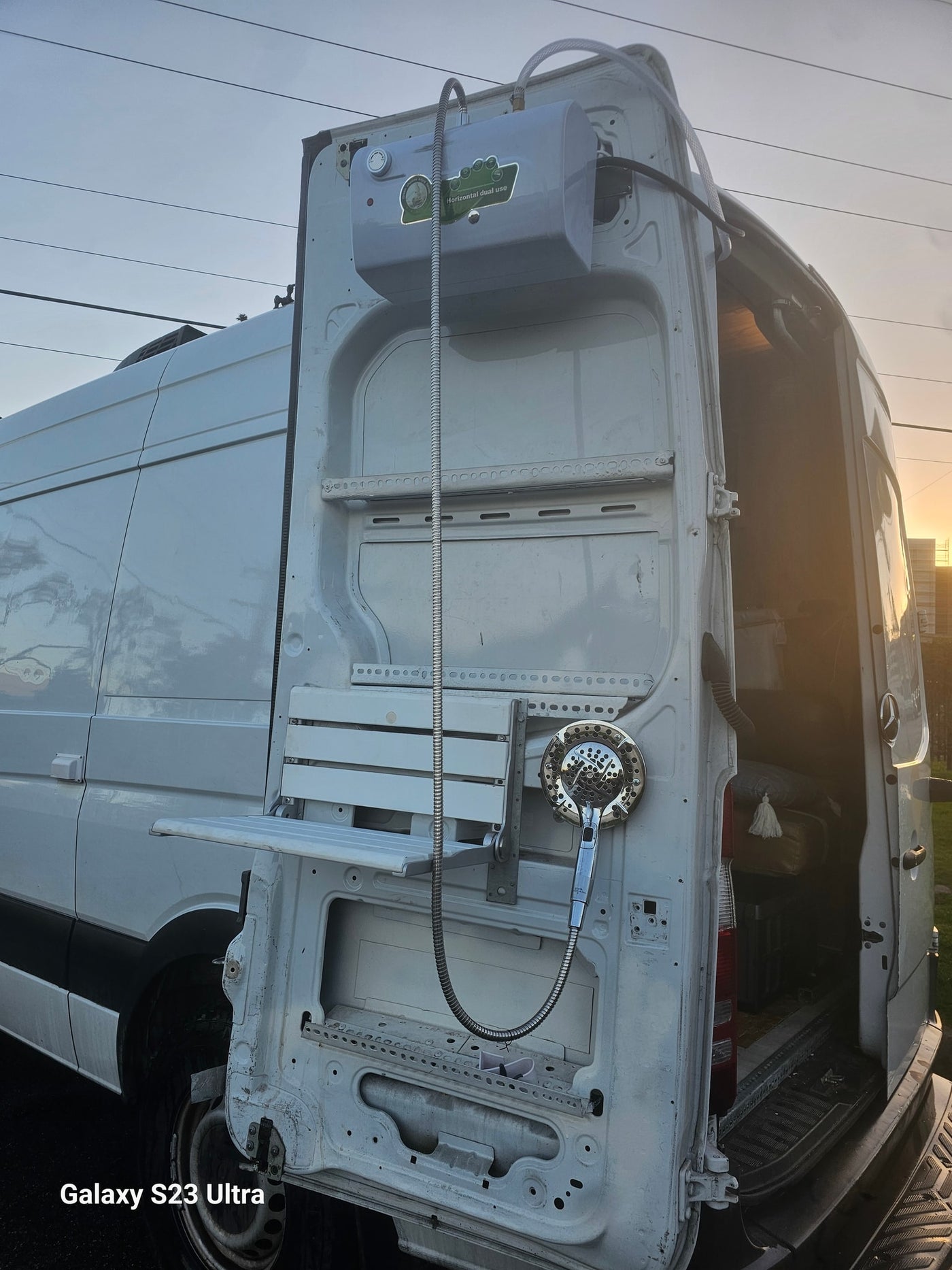  parked on a street in front of a brick building.|Compact camper van RV rental interior features a convertible bench/bed — photo 18