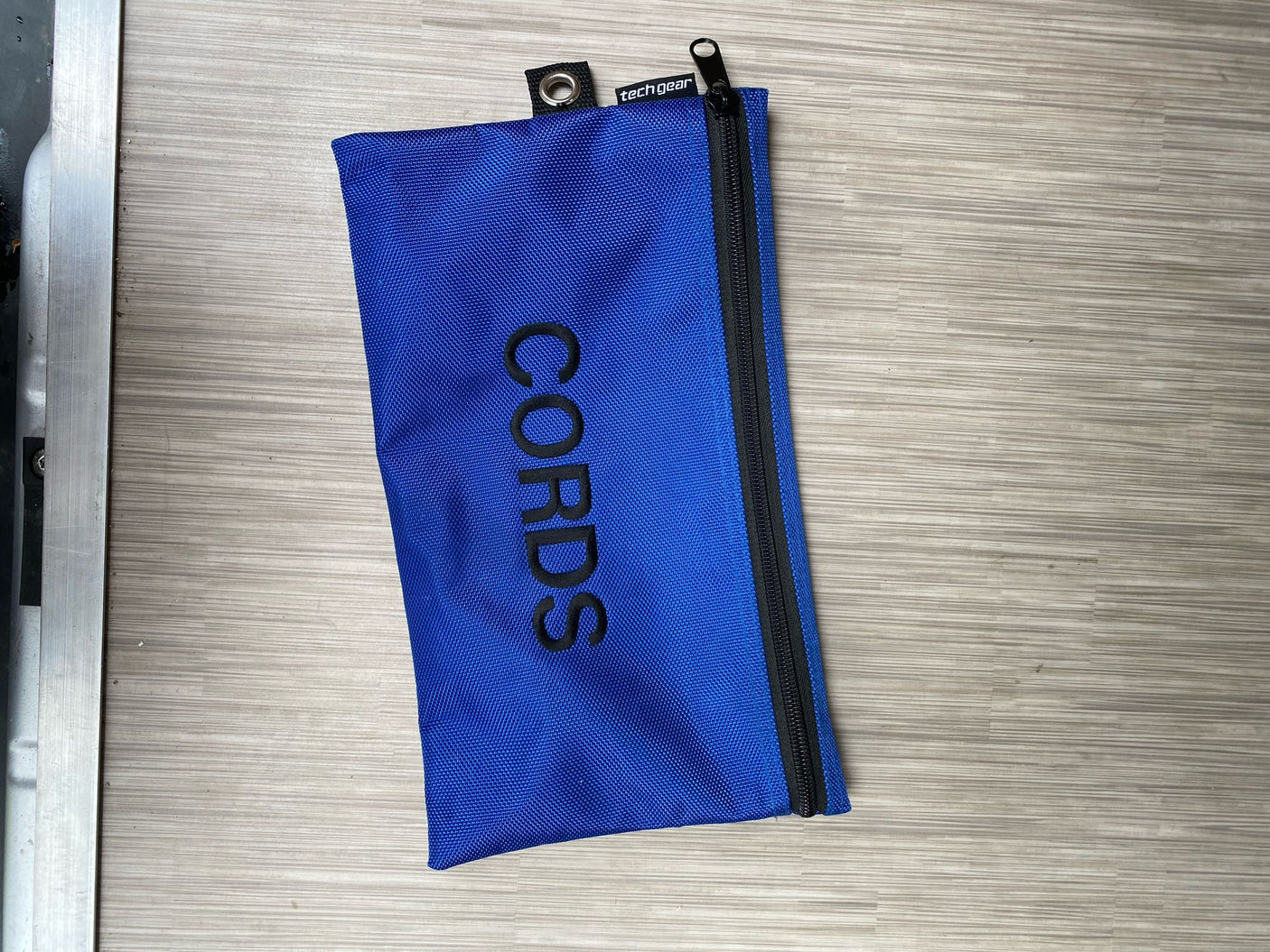 A blue "CORDS" tech gear pouch, ideal for organizing cables and items in your RV rental.