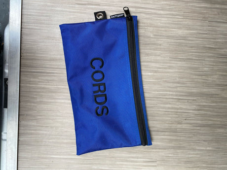 A blue "CORDS" tech gear pouch, ideal for organizing cables and items in your RV rental.
