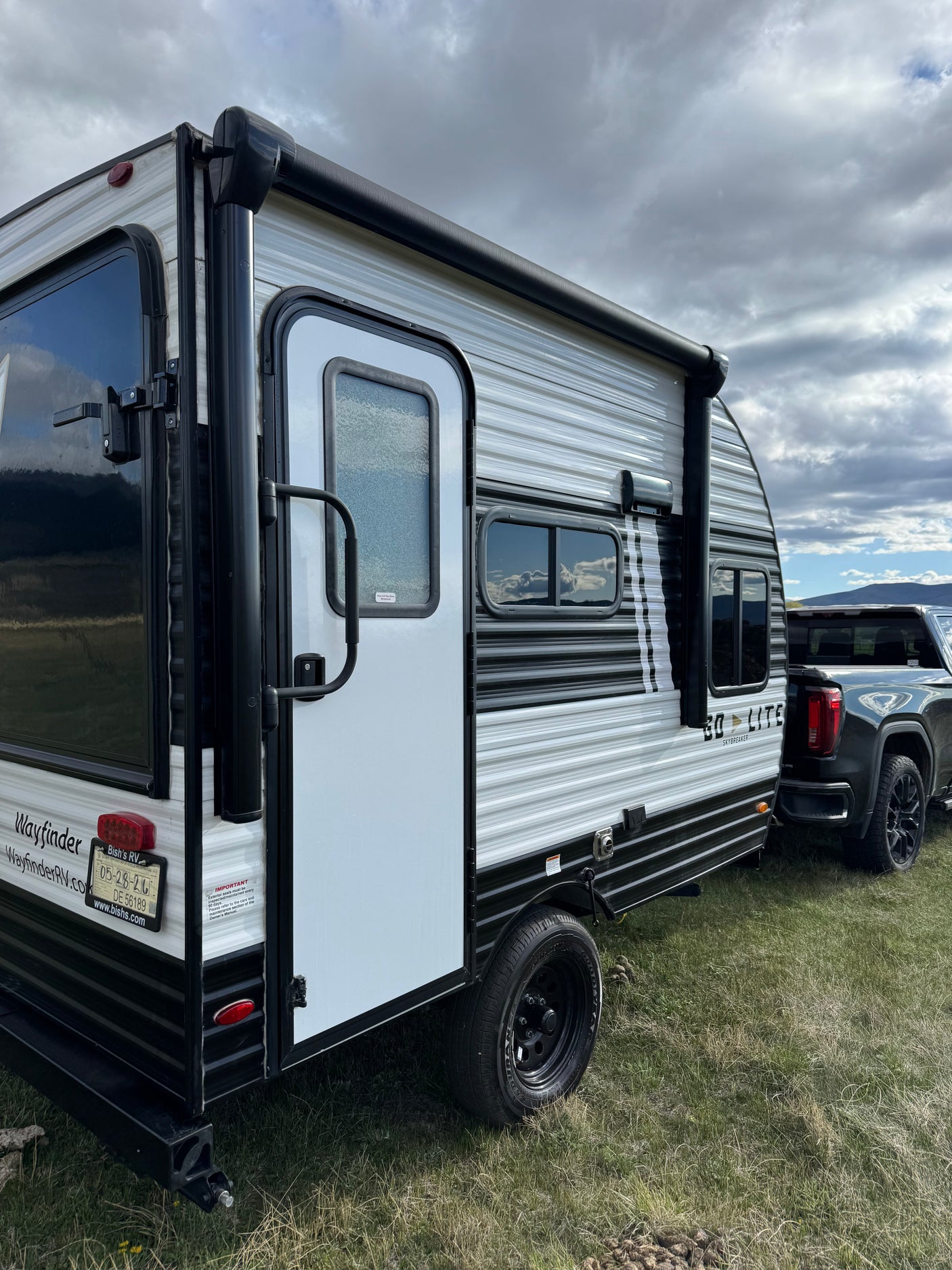 Wayfinder travel trailer RV rental, a Skybreaker model, hitched to a truck on grass, perfect for your next outdoor trip.