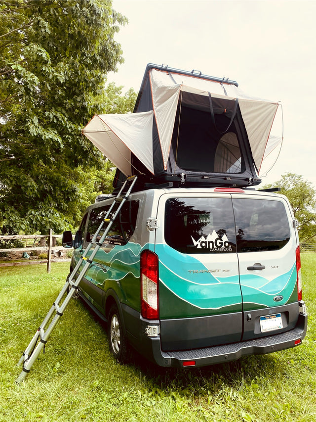 Custom RV rental Ford Transit van, equipped with a rooftop tent and ladder, parked on grass. Ideal for mobile adventures.