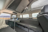 Cozy RV rental interior with pop-top, dining setup, and scenic views, perfect for mobile living on your road trip.
