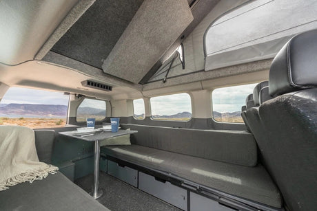 Cozy RV rental interior with pop-top, dining setup, and scenic views, perfect for mobile living on your road trip.