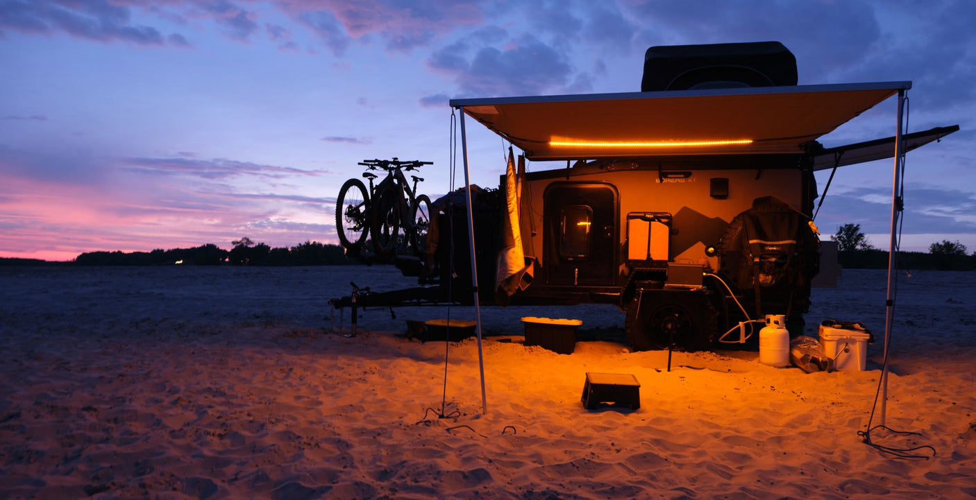 Adventure awaits! This off-road **rv rental**, with bikes and warm lights, is ready for camping at sunset on the sand.